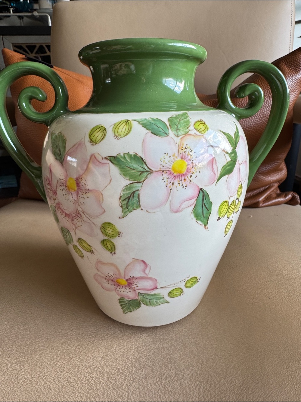 ceramic vase featuring flower motif and a green rim with double handles